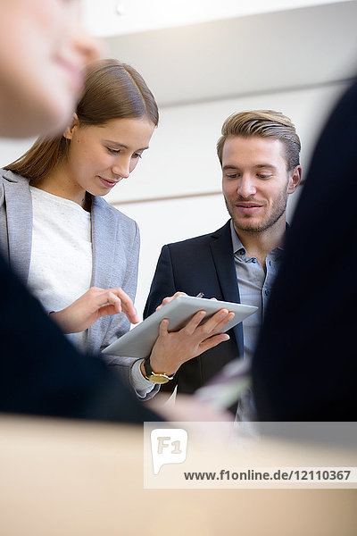 Junge Geschäftsfrau und Mann benutzen digitalen Tablet-Touchscreen am Konferenztisch