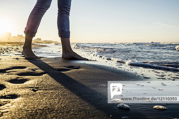 Beine einer barfüssigen Frau  die am Strand am Wasser steht  Riccione  Emilia-Romagna  Italien
