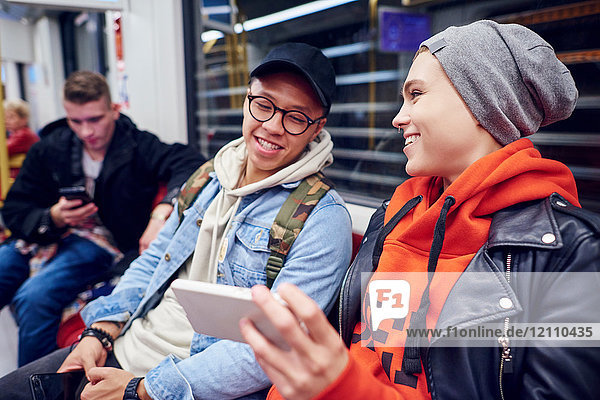 Junges Paar wartet in U-Bahn-Station und schaut auf Smartphone