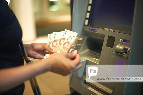 Geschnittene Ansicht einer Frau  die Geld am Geldautomaten abhebt
