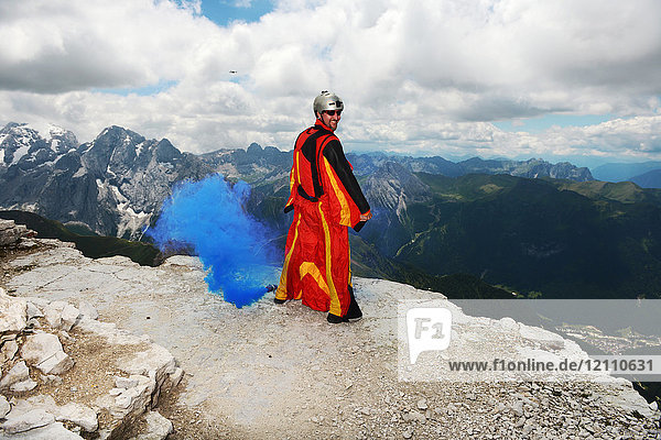 Base jumper on Dolomite mountains wearing wingsuit emitting blue smoke  Canazei  Trentino Alto Adige  Italy  Europe