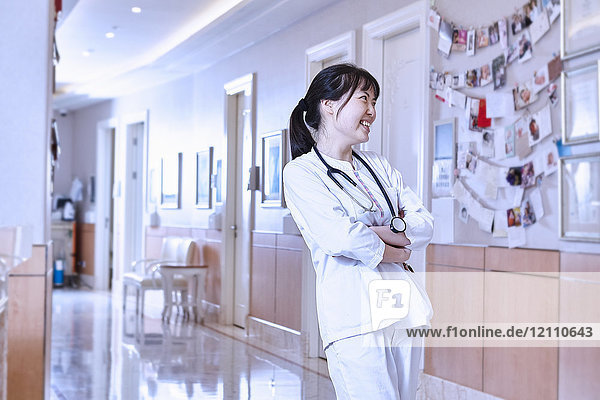 Porträt eines Arztes im Krankenhauskorridor  der lächelnd wegschaut