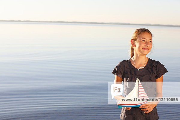 Junges Mädchen  steht am Wasser  hält Spielzeugboot