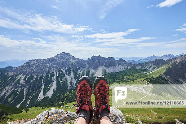 Personal perspective of female hiker's hiking boots over valley in Tannheim mountains  Tyrol  Austria