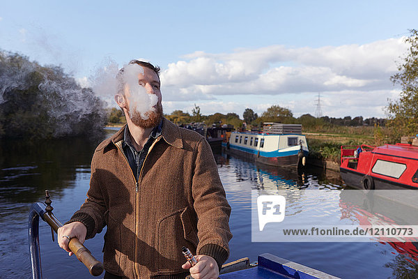 Mann raucht E-Zigarette auf Kanalboot