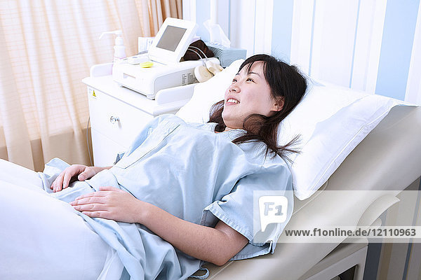 Schwangere Frau im Krankenhausbett liegend
