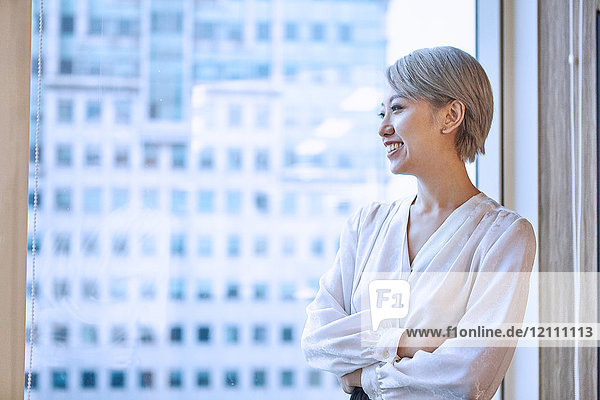 Portrait of businesswoman looking out of window smiling
