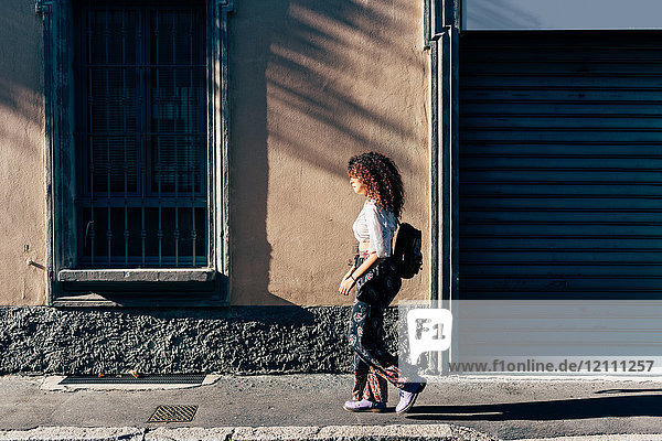 Woman passing roller shutters of closed shop  Milan  Italy