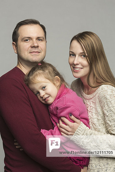 Portrait of happy parents with daughter against gray background
