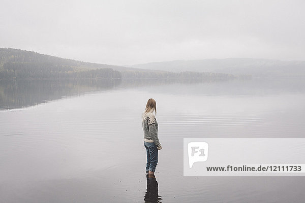 Frau steht im See gegen den Himmel bei nebligem Wetter  Jaervsoe  Haelsingland  Schweden
