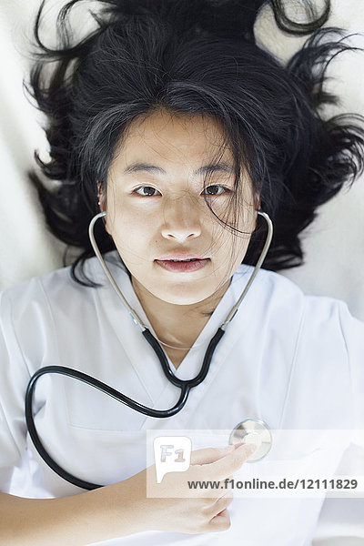 Hochwinkelporträt einer Ärztin  die den Selbstherzschlag mit dem Stethoskop hört.