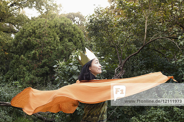 Rückansicht der Frau mit Krone und orangem Schal gegen Bäume im Park