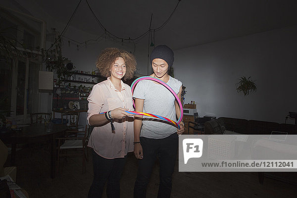 Mann und Frau halten Plastikreifen  während sie zu Hause stehen.