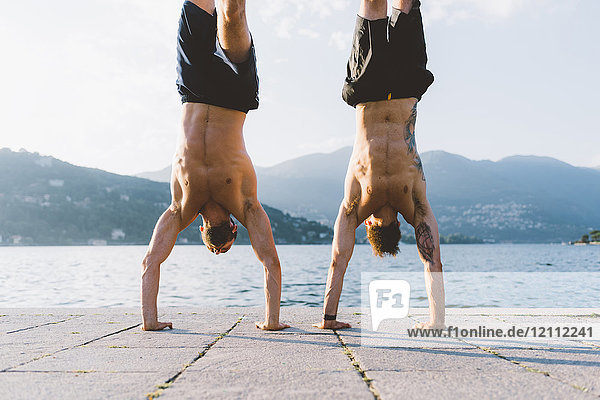 Two young men doing handstands on waterfront  Lake Como  Lombardy  Italy