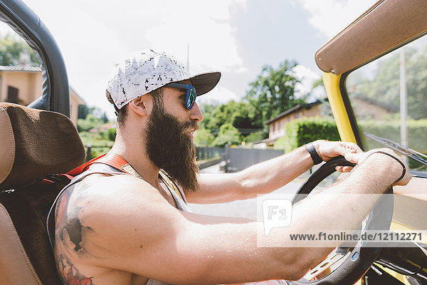 Young male hipster driving off road vehicle on road trip  Como  Lombardy  Italy