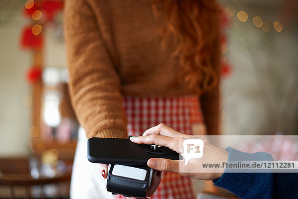 Customer in cafe making contactless payment with mobile phone