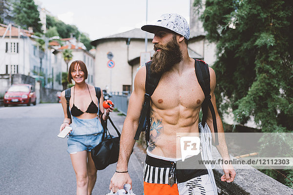 Young couple in swimwear and backpacks strolling in Como  Lombardy  Italy