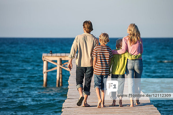 Rear view of family walking on pier