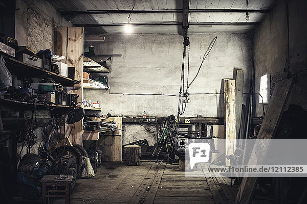 Mechanic sitting in armchair looking at dismantled vintage motorcycle in workshop
