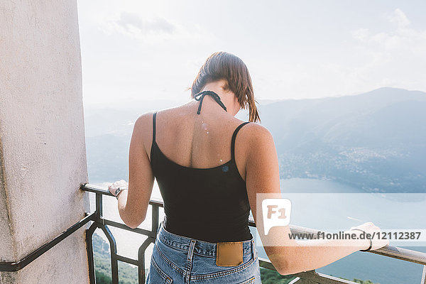 Rear view of young woman on viewing platform looking down at Lake Como  Lombardy  Italy