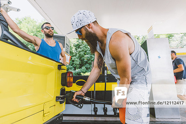 Junger männlicher Hipster beim Tanken eines Geländewagens an einer Tankstelle auf Autoreise  Como  Lombardei  Italien