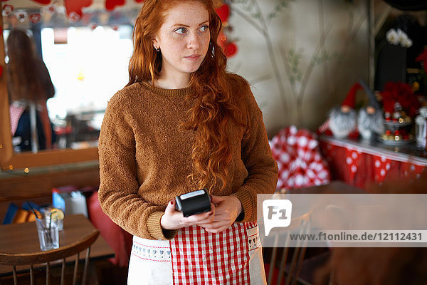 Waitress in cafe holding credit card reader