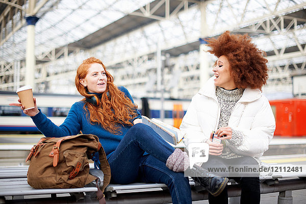 Friends on bench on train station platform  London