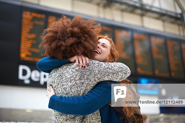 Zwei junge Frauen umarmen sich am Bahnhof