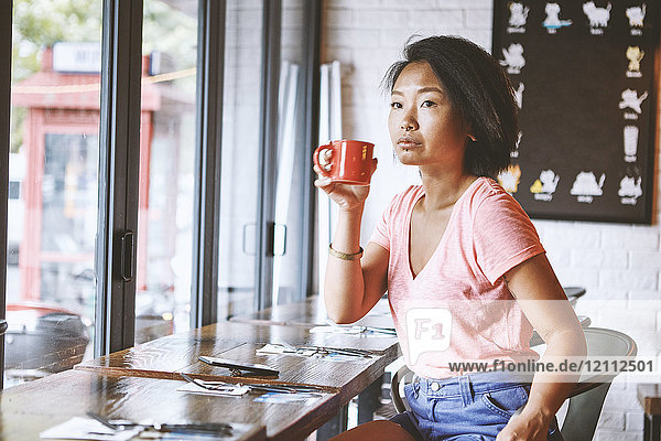 Woman in cafe watching from window seat  Shanghai French Concession  Shanghai  China