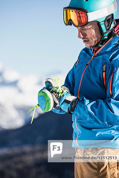 Mature man wearing skiwear  putting on ski gloves