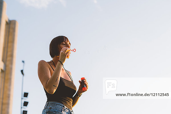 Young woman blowing bubbles against blue sky  Como  Lombardy  Italy