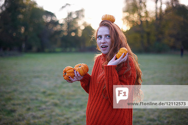 Young woman in rural setting  holding pumpkins  pumpkin balanced in head