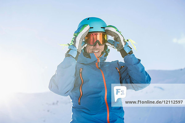 Portrait of skier  adjusting goggles