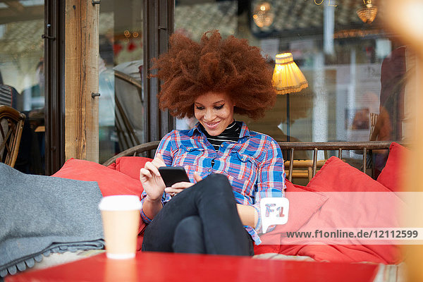 Frau im Café mit Mobiltelefon