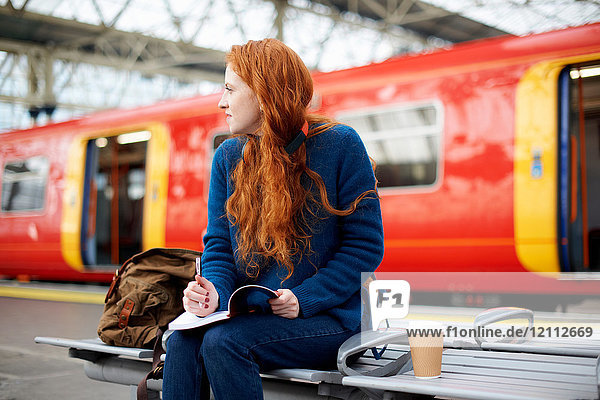 Woman on bench on train station platform  London
