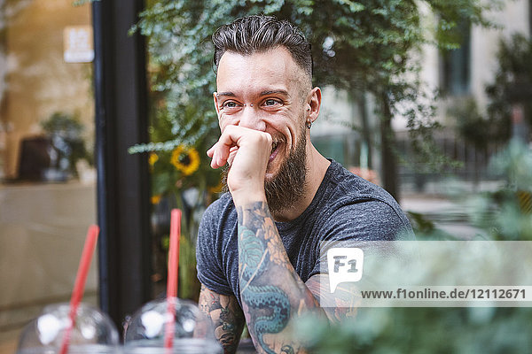 Junger männlicher Hipster lacht im Bürgersteig-Café  Shanghai Französische Konzession  Shanghai  China
