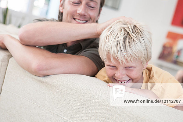 Father and son relaxing on sofa smiling