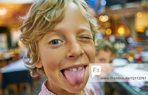 Portrait of boy looking at camera poking out tongue