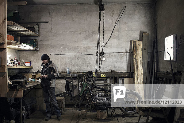 Mechanic looking at workbench in workshop with dismantled vintage motorcycle