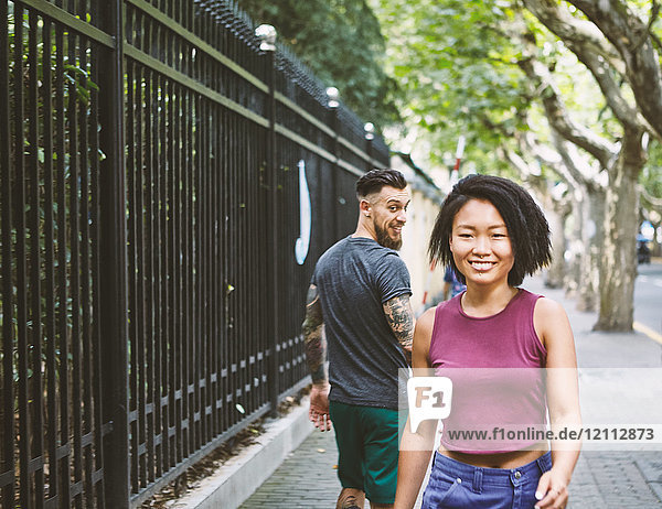 Junger männlicher Hipster blickt zurück auf Frau auf dem Bürgersteig  Shanghai Französische Konzession  Shanghai  China