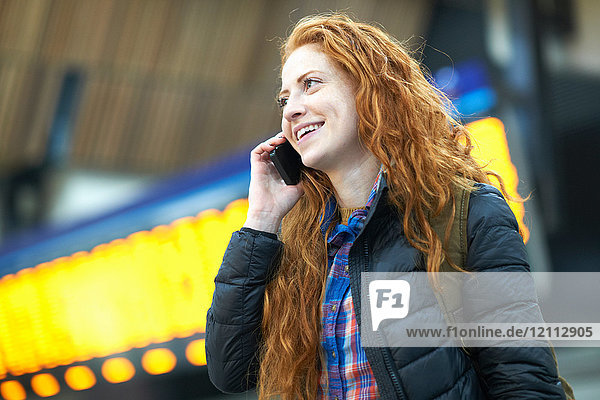 Young woman at train station  talking on smartphone