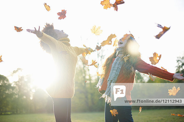 Friends throwing autumn leaves in air