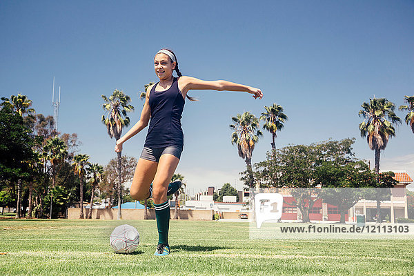 Schulmädchen-Fussballspielerin kickt Ball auf Schulsportplatz