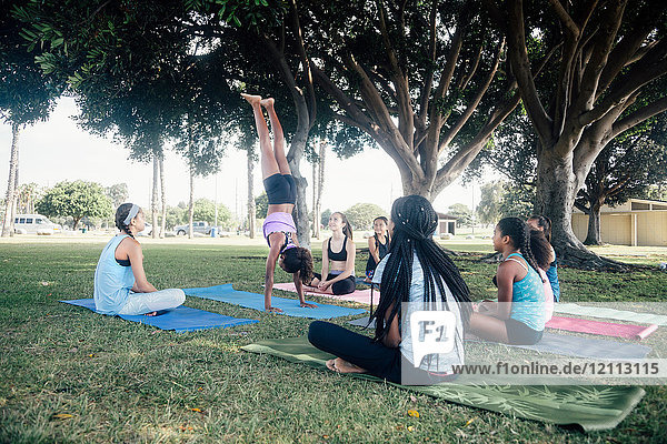 Schülerinnen üben Yoga-Handstand auf dem Schulsportplatz