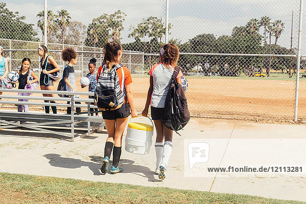 Mädchen und Teenager-Schülerinnen tragen Getränkekühler auf dem Schulsportplatz
