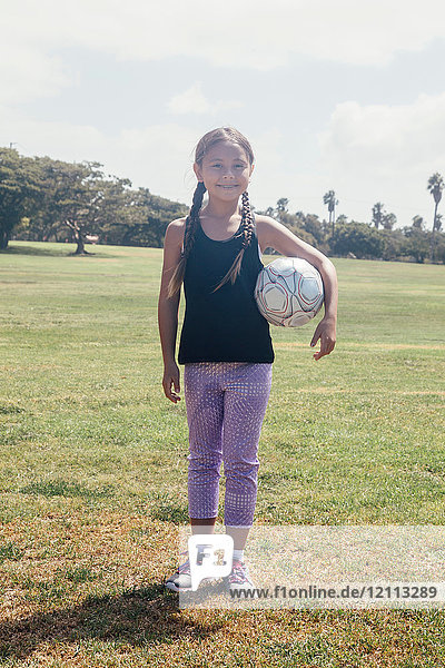 Portrait of schoolgirl holding soccer ball on school sports field