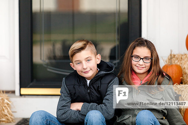 Portrait of boy and twin sister in front porch