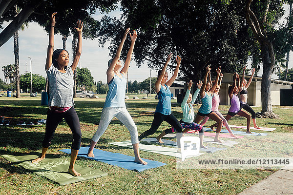 Schulmädchen üben Yoga-Krieger eine Pose auf dem Schulsportplatz