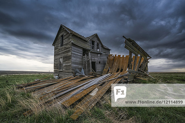 Verlassenes Haus in der Prärie mit Sturmwolken über dem Kopf bei Sonnenuntergang; Val Marie  Saskatchewan  Kanada