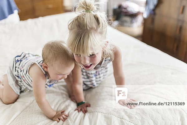 Zwei Schwestern  ein Baby und ein Kleinkind  spielen zusammen auf einem Bett; Sorrento  British Columbia  Kanada
